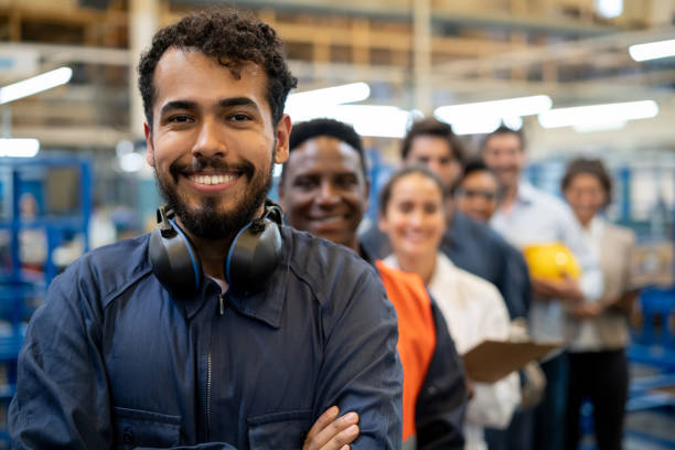 manufacturing worker and team of engineers at a factory standing in a row for communication