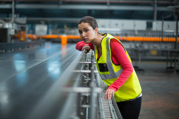 Female worker checking conveyor belt at manufacturing factory mapping value stream