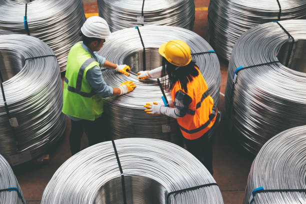 Aerial view of engineer man and industrial worker woman checking metal production line and testing quality of steel pipe coils