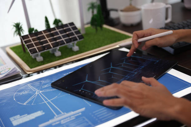 professional working on tablet with a mock-up display. Creating Concept of Wind Turbine and solar panel energy.