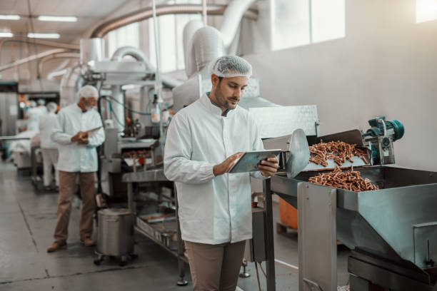 supervisor evaluating quality of food in food plant while holding tablet