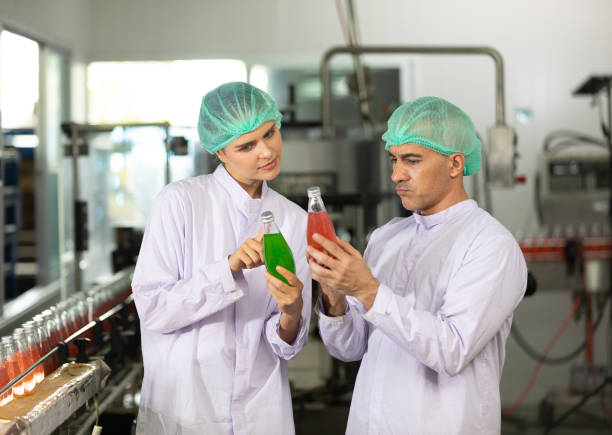 two Food Manufacturing Consultants talking and checking quality of basil seed drink in a food and beverage factory