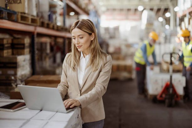 Female inventory manager working with computer laptop in storage warehouse