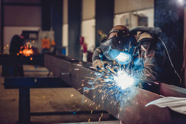 Industrial Welder With Torch and Protective Helmet in big hall welding metal working