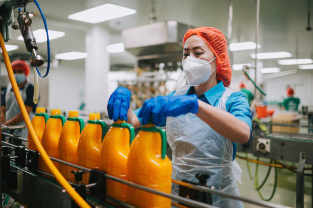 female juice factory worker tighten bottle cap in food production line