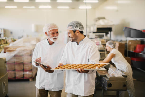 Picture of two employees in sterile clothes in a food manufacturing factory smiling and talking