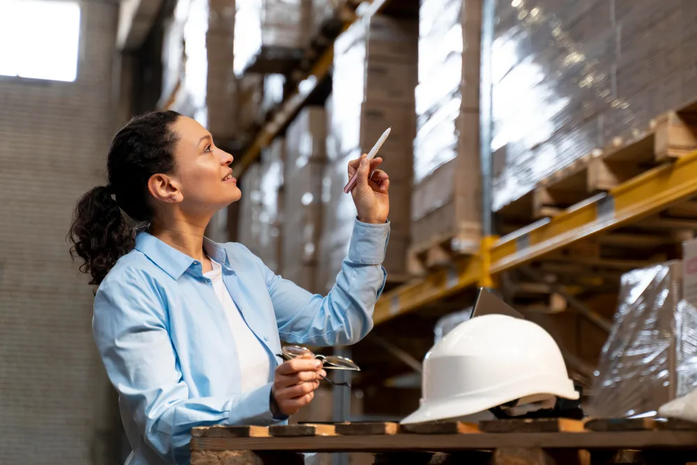 Woman inspecting warehouse inventory as part of manufacturing business strategies focused on process optimization, automation, and workforce training