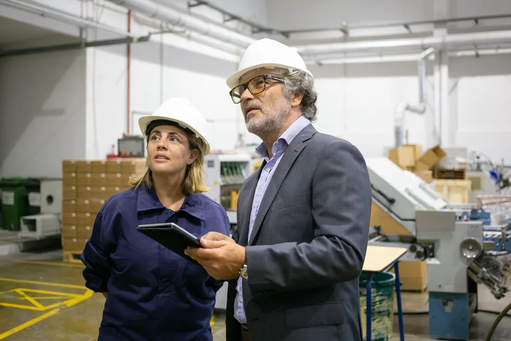 Supervisors reviewing lean manufacturing best practices on factory floor to improve efficiency and productivity